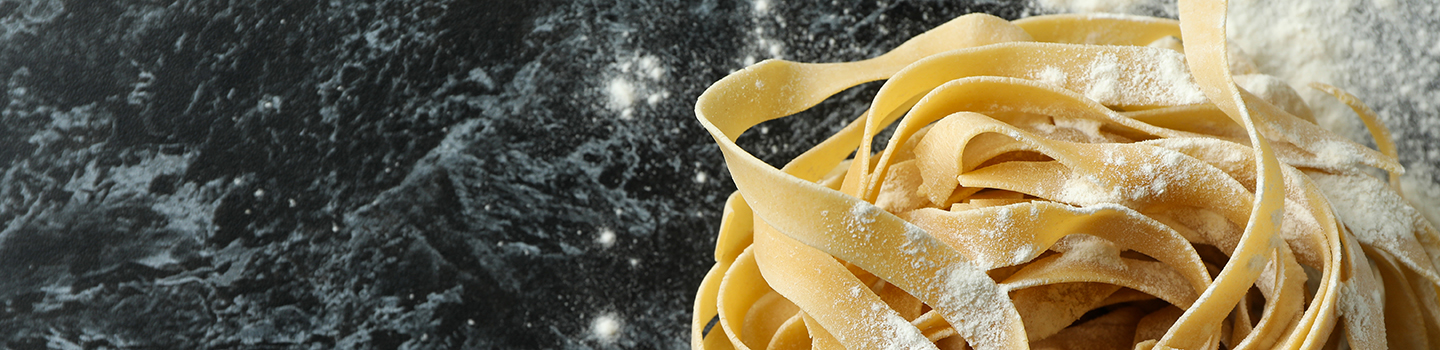 Uncooked pasta with flour on black smokey background